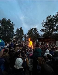 сценографија божићне вечери на златибору са украшеним храмом и великим пламеном бадњака који греје окупљене вернике