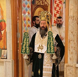 Свечани призор Свете архијерејске литургије у Храму Преображења Господњег којом чинодејствује митрополит жички Јустин у раскошној златној одори окружен свештенством и верним народом у молитвеној тишини испред богатог иконостаса